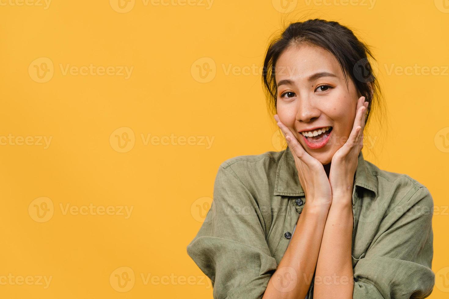 jeune femme asiatique à l'expression positive, sourire largement, vêtue de vêtements décontractés et regardant la caméra sur fond jaune. heureuse adorable femme heureuse se réjouit du succès. concept d'expression faciale. photo