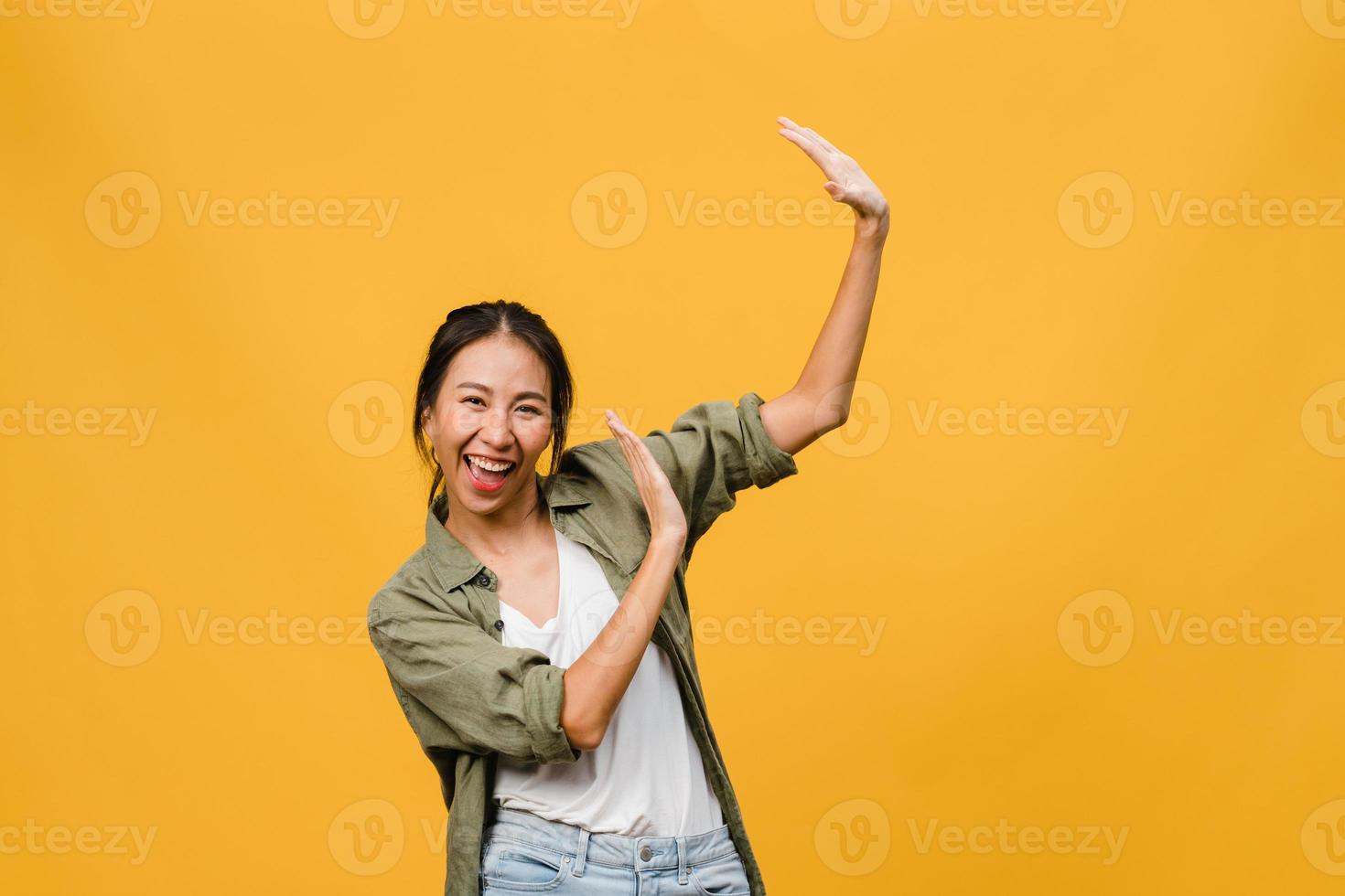 portrait d'une jeune femme asiatique avec une expression positive, un large sourire, vêtue de vêtements décontractés sur fond jaune. heureuse adorable femme heureuse se réjouit du succès. concept d'expression faciale. photo