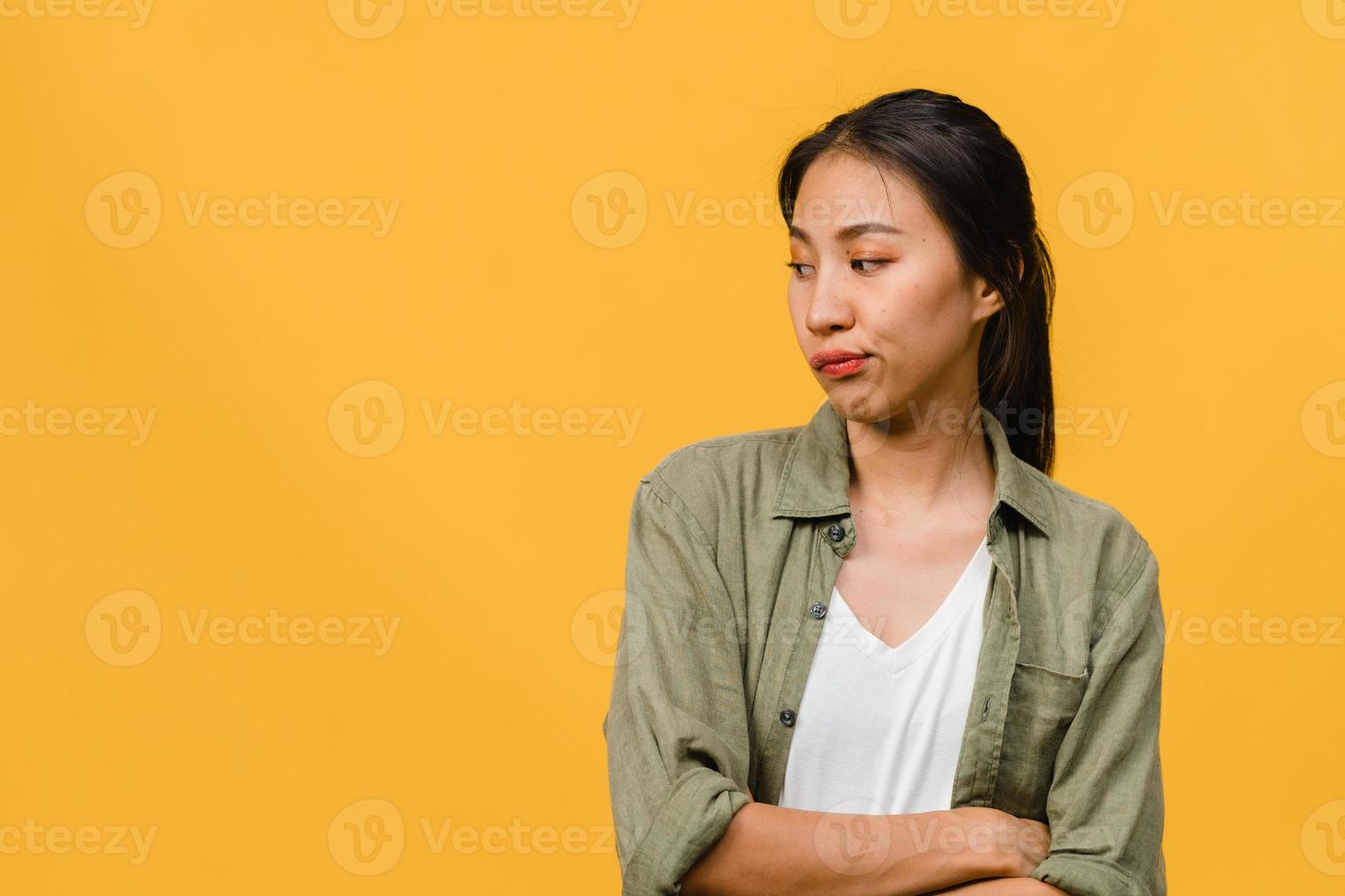 portrait d'une jeune femme asiatique avec une expression négative, des cris excités, des pleurs émotionnels en colère dans des vêtements décontractés isolés sur fond jaune avec un espace de copie vierge. concept d'expression faciale. photo