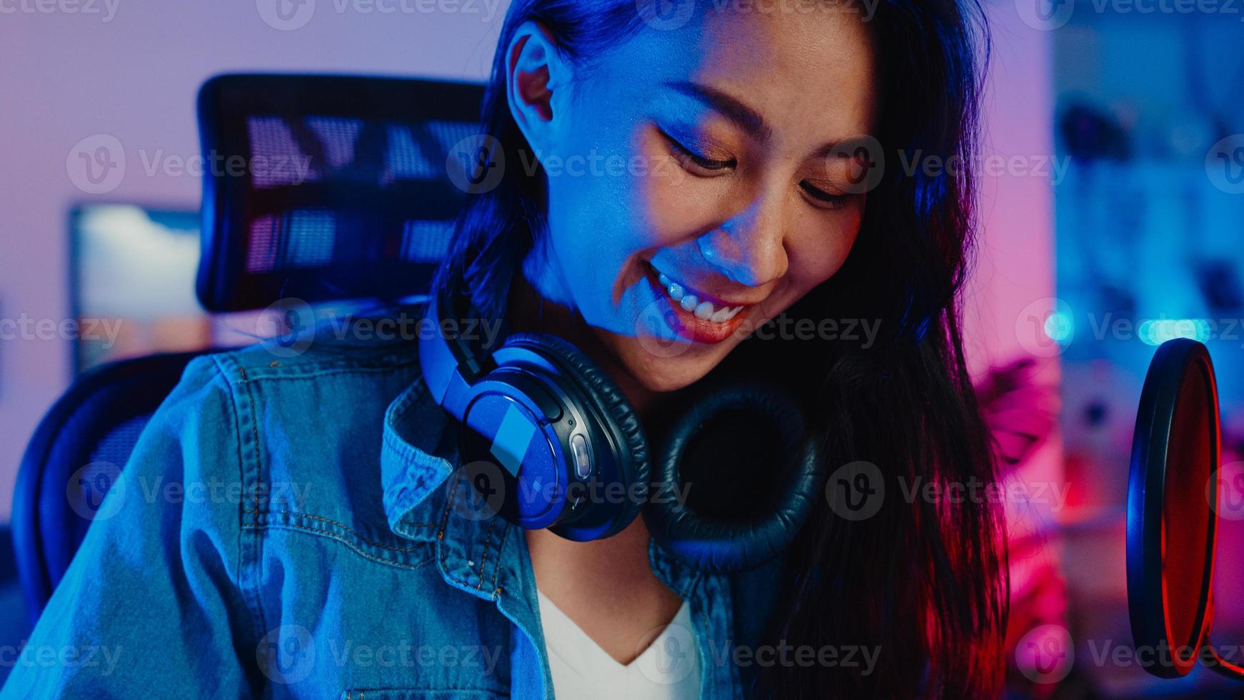 Une blogueuse asiatique heureuse joue au clavier de synthétiseur, porte un casque et enregistre de la musique avec un mixeur de son sur un ordinateur portable dans le studio du salon la nuit. créateur de contenu musical, tutoriel, concept de diffusion. photo