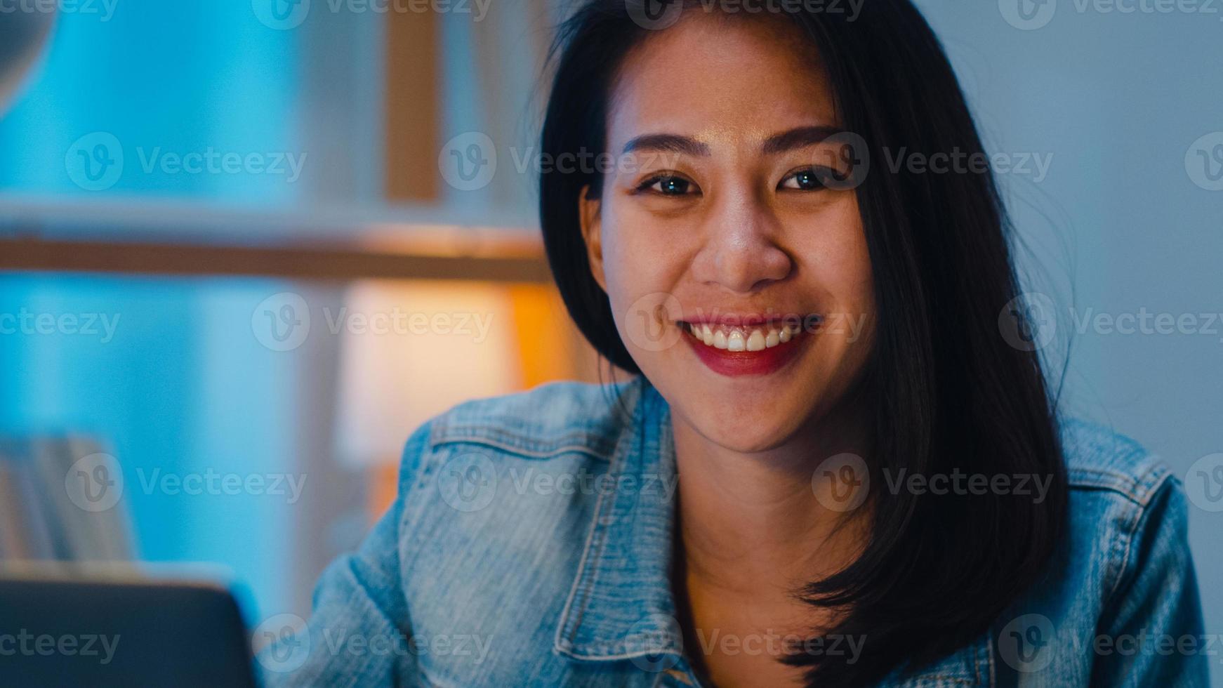 joyeuse jeune graphiste utilisant une tablette graphique numérique tout en travaillant tard dans un bureau moderne la nuit, une femme professionnelle asiatique utilisant un retoucheur d'ordinateur portable assis dans le salon à la maison. photo