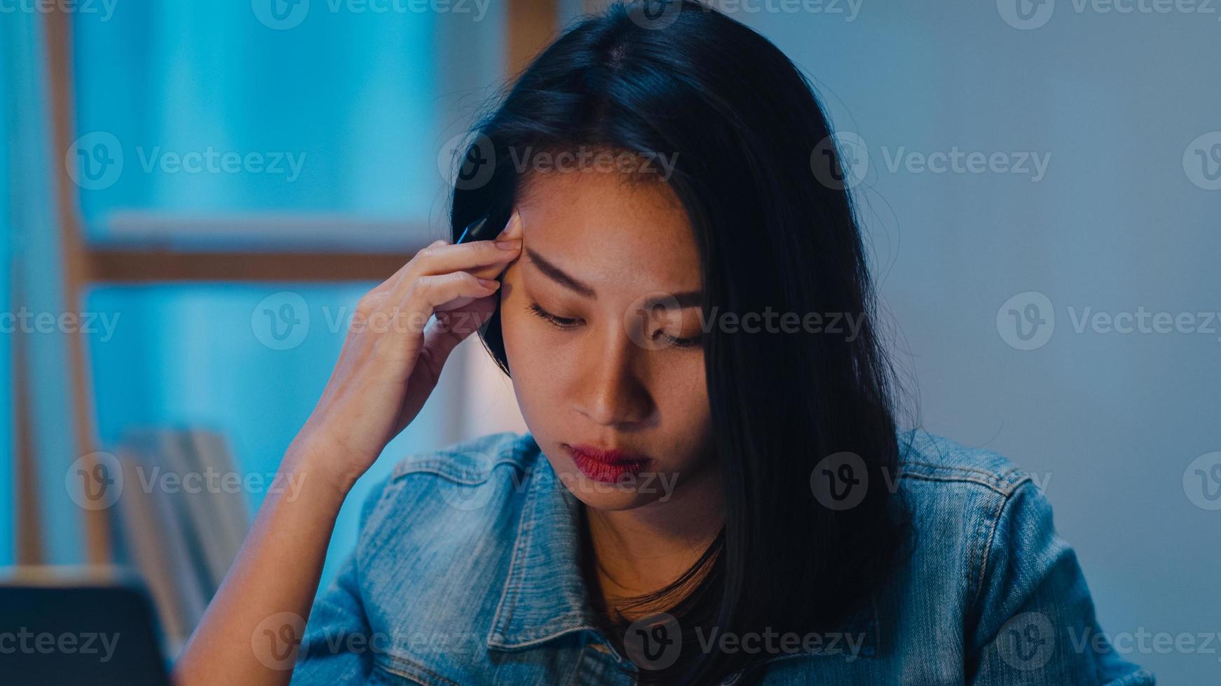 Jeune femme d'affaires chinoise millénaire travaillant tard dans la nuit avec un problème de recherche de projet sur un ordinateur portable dans le salon d'une maison moderne. concept de syndrome d'épuisement professionnel des personnes d'asie. photo