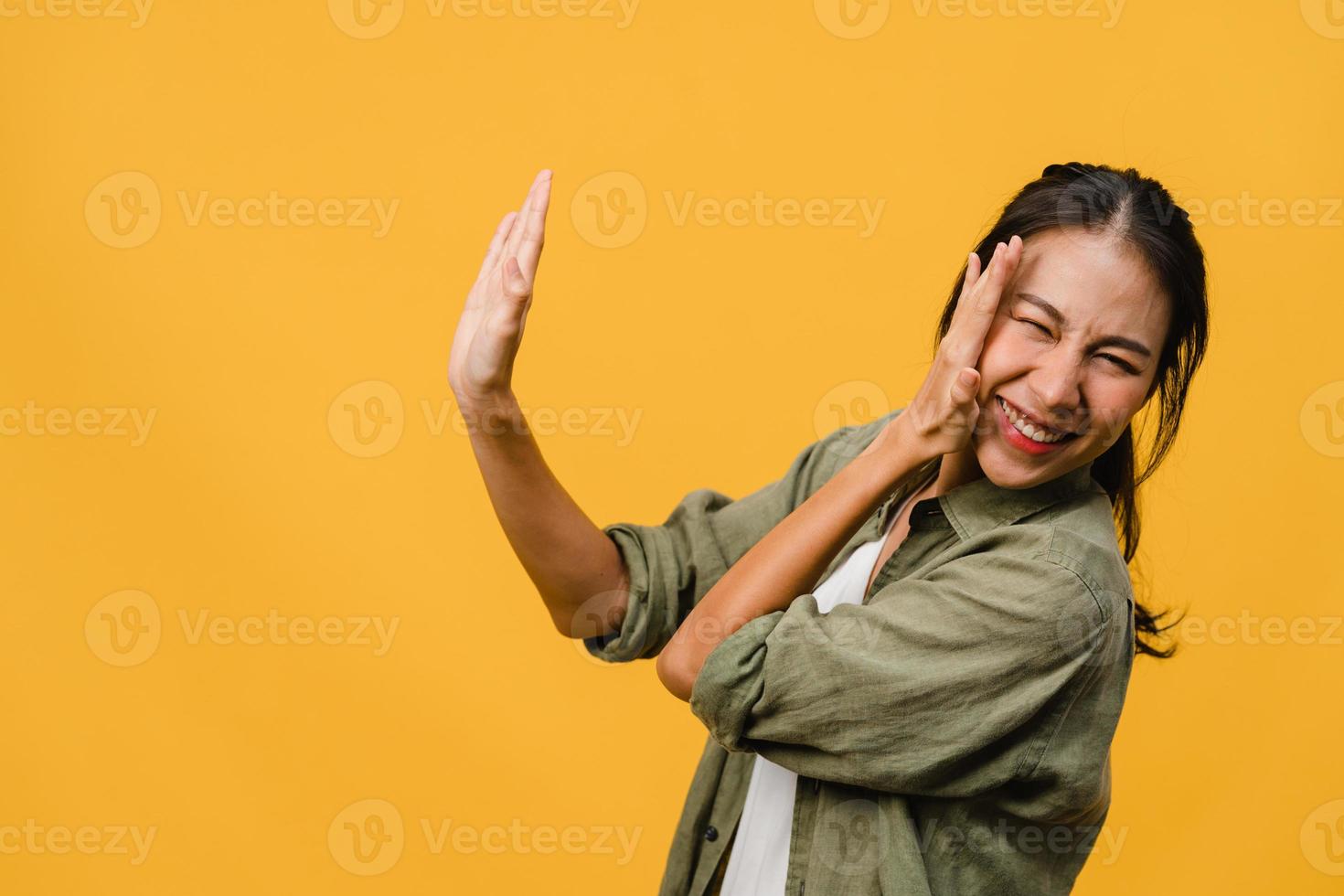 la jeune femme asiatique ressent le bonheur avec une expression positive, une joyeuse surprise funky, vêtue d'un tissu décontracté isolé sur fond jaune. heureuse adorable femme heureuse se réjouit du succès. expression faciale. photo