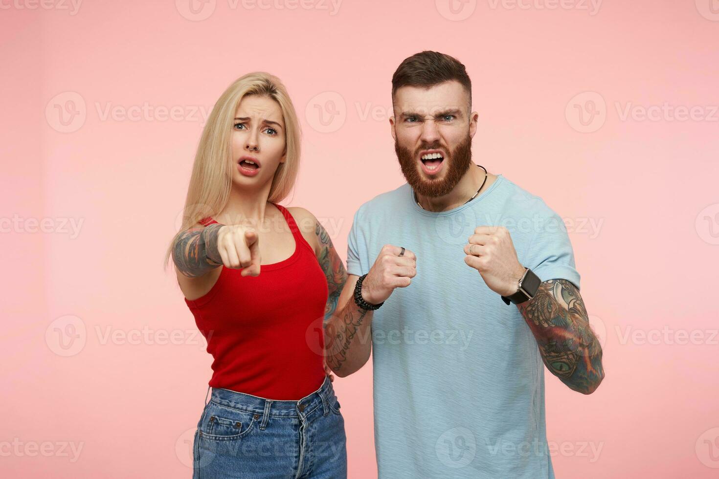 offensé Jeune jolie longue aux cheveux blond femelle montrant à sa sérieux en colère brunette barbu gars Quelqu'un qui fabriqué sa triste, isolé plus de rose Contexte photo