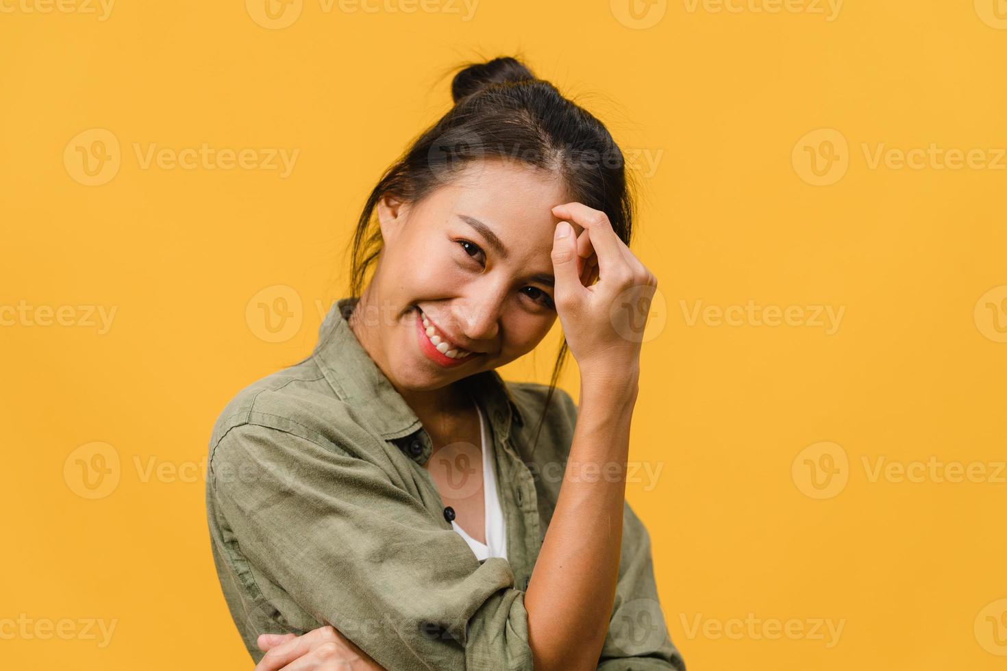 jeune femme asiatique à l'expression positive, sourire largement, vêtue de vêtements décontractés et regardant la caméra sur fond jaune. heureuse adorable femme heureuse se réjouit du succès. concept d'expression faciale. photo