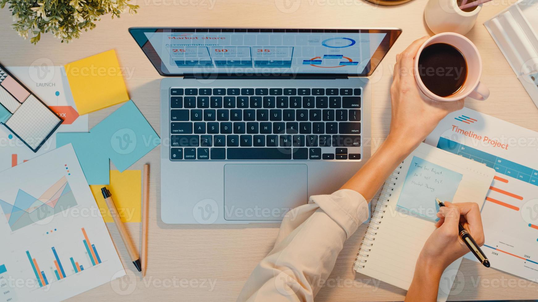 vue de dessus d'une jeune femme d'affaires asiatique indépendante se concentrant sur un ordinateur portable écrire une feuille de calcul financière graphique compte plan de marché au bureau la nuit. travail à domicile, à distance, concept de coronavirus d'enseignement à distance photo