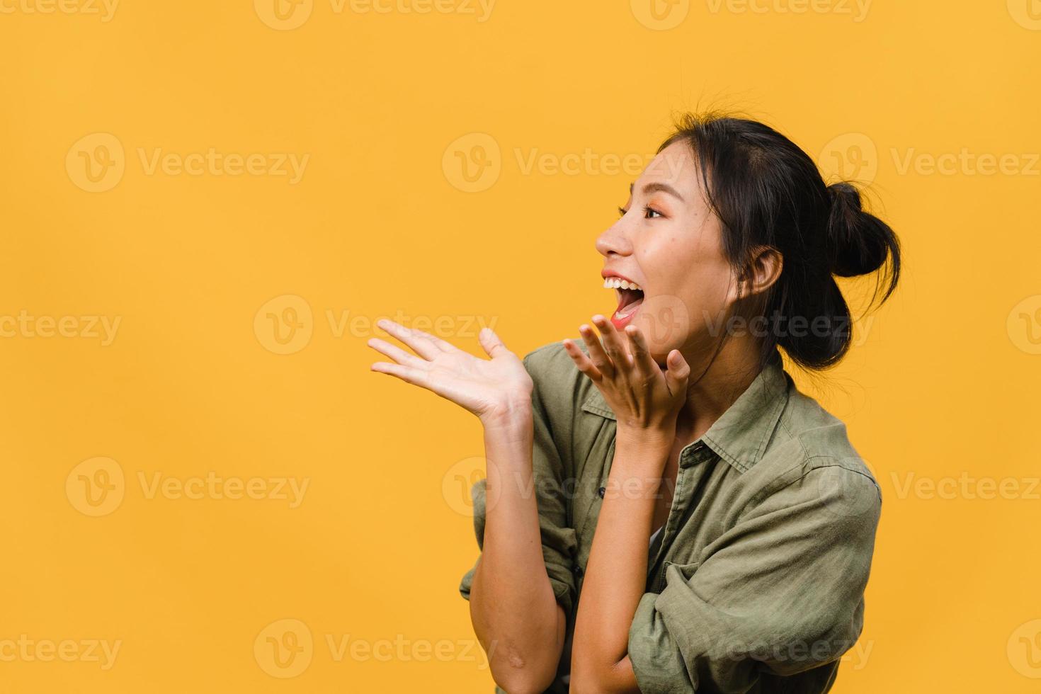 la jeune femme asiatique ressent le bonheur avec une expression positive, une joyeuse surprise funky, vêtue d'un tissu décontracté isolé sur fond jaune. heureuse adorable femme heureuse se réjouit du succès. expression faciale. photo