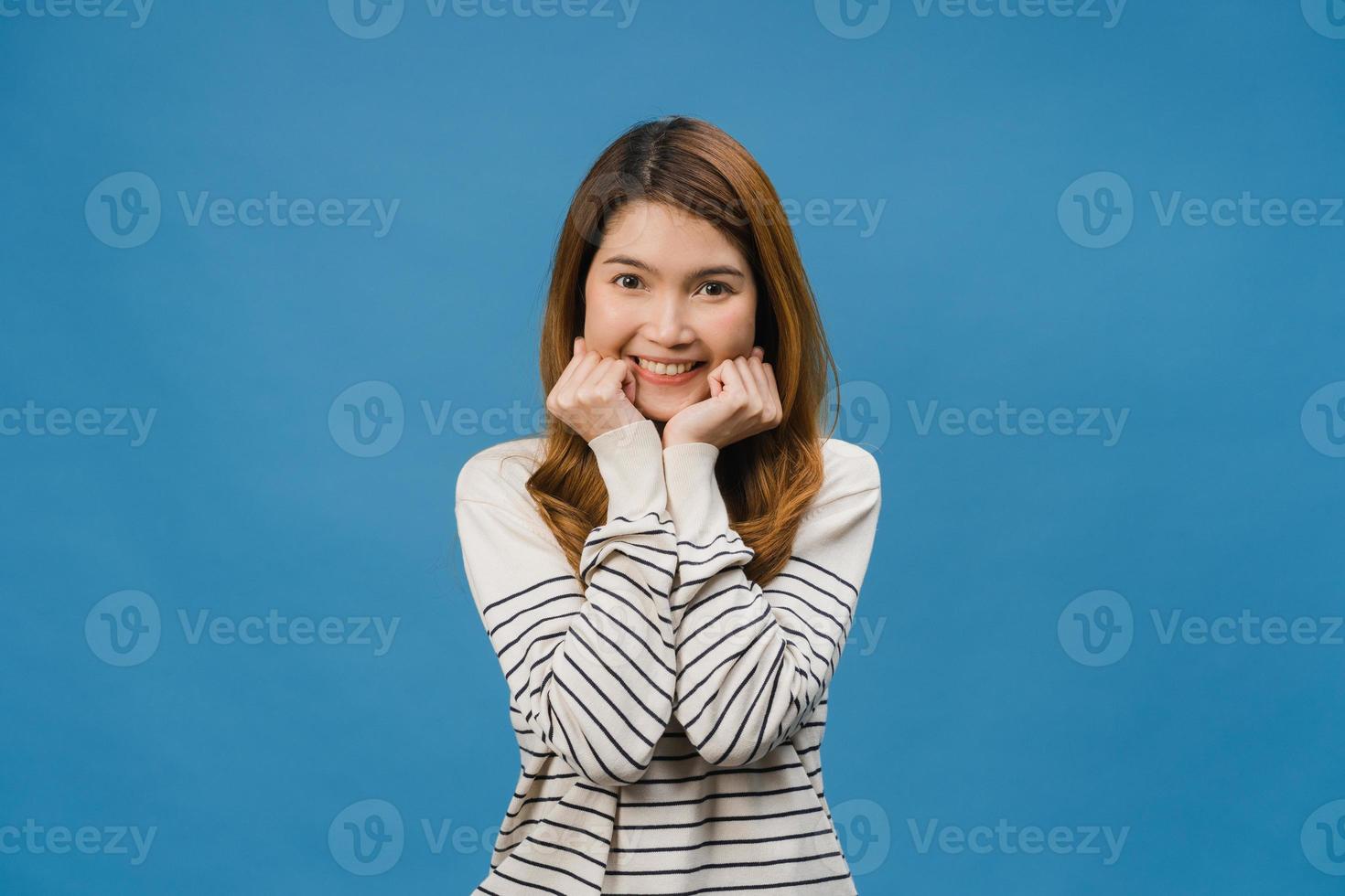 jeune femme asiatique à l'expression positive, sourire largement, vêtue de vêtements décontractés et regardant la caméra sur fond bleu. heureuse adorable femme heureuse se réjouit du succès. concept d'expression faciale. photo