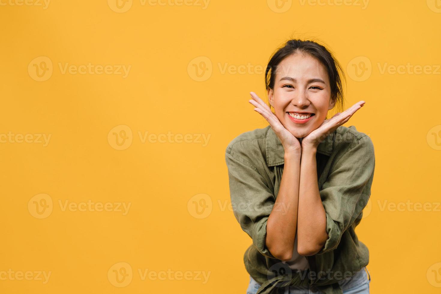 jeune femme asiatique à l'expression positive, sourire largement, vêtue de vêtements décontractés et regardant la caméra sur fond jaune. heureuse adorable femme heureuse se réjouit du succès. concept d'expression faciale. photo