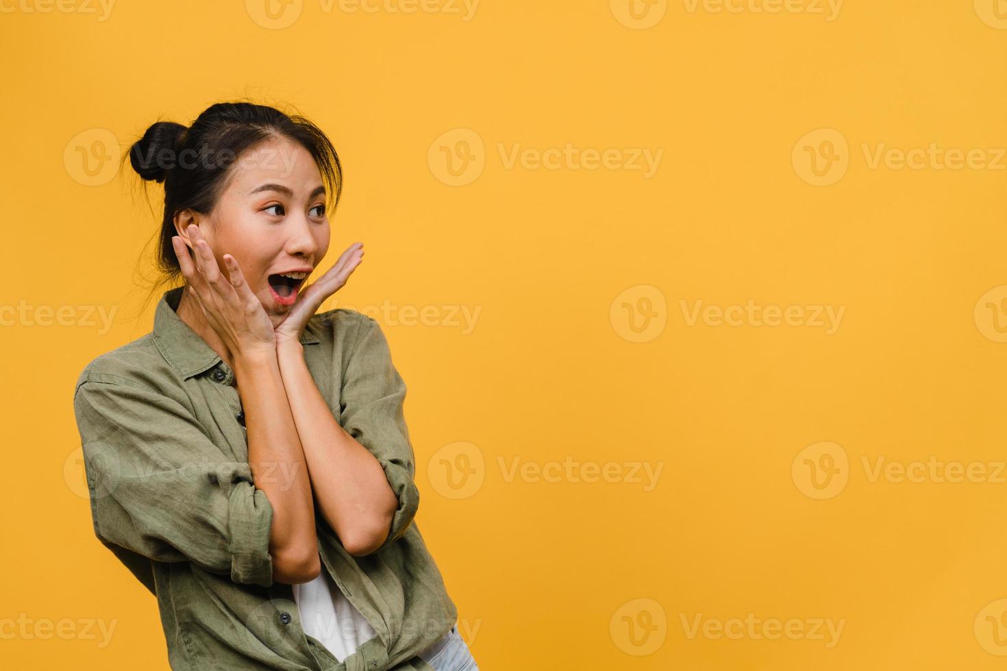 la jeune femme asiatique ressent le bonheur avec une expression positive, une joyeuse surprise funky, vêtue d'un tissu décontracté isolé sur fond jaune. heureuse adorable femme heureuse se réjouit du succès. expression faciale. photo