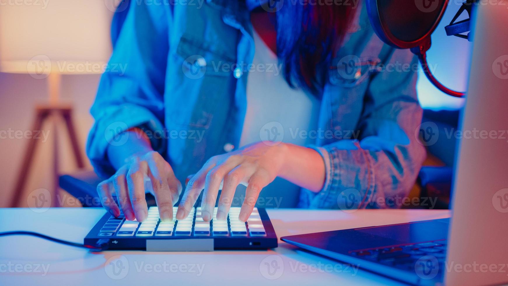 close-up happy asia girl dj utiliser launchpad synthétiseur clavier mixeur de son porter un casque fait de la musique dans un ordinateur portable en ligne en direct dans le salon home studio la nuit. concept de créateur de contenu. photo