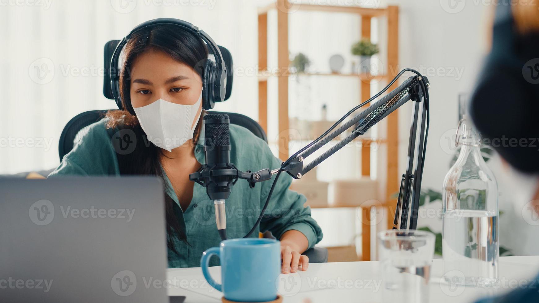 asia girl radio host record podcast utiliser microphone porter un casque interview contenu invité porter un masque protéger virus conversation parler et écouter dans sa chambre. podcast de la maison, quarantaine de coronavirus. photo