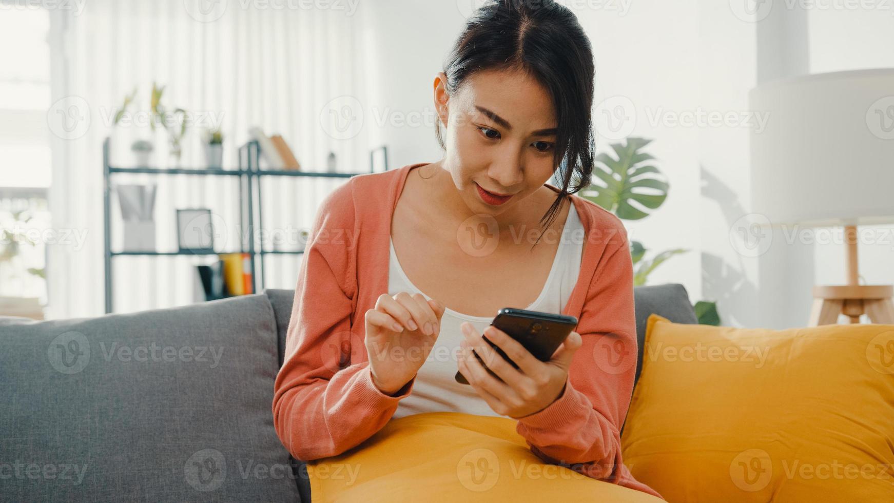 belle dame utilisant un chat sur smartphone avec un couple assis sur un canapé dans le salon à la maison le matin. rester à la maison, quarantaine pour covid, nomophobie, achats en ligne, concept de dépendance aux réseaux sociaux. photo