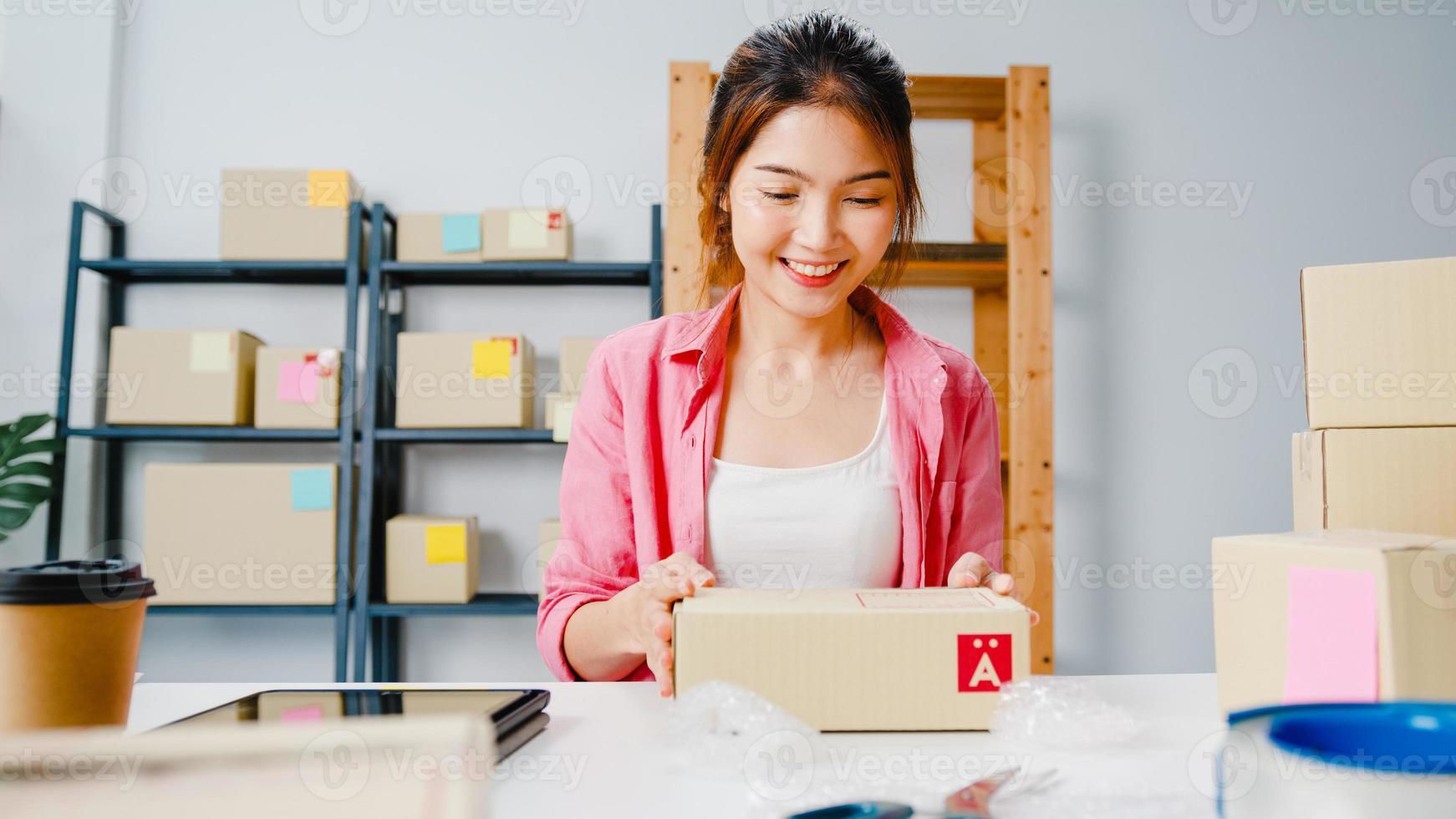 jeune entrepreneur asiatique femme d'affaires emballant le produit dans une boîte en carton livrer au client, travaillant au bureau à domicile. propriétaire de petite entreprise, démarrage de la livraison sur le marché en ligne, concept de style de vie indépendant. photo