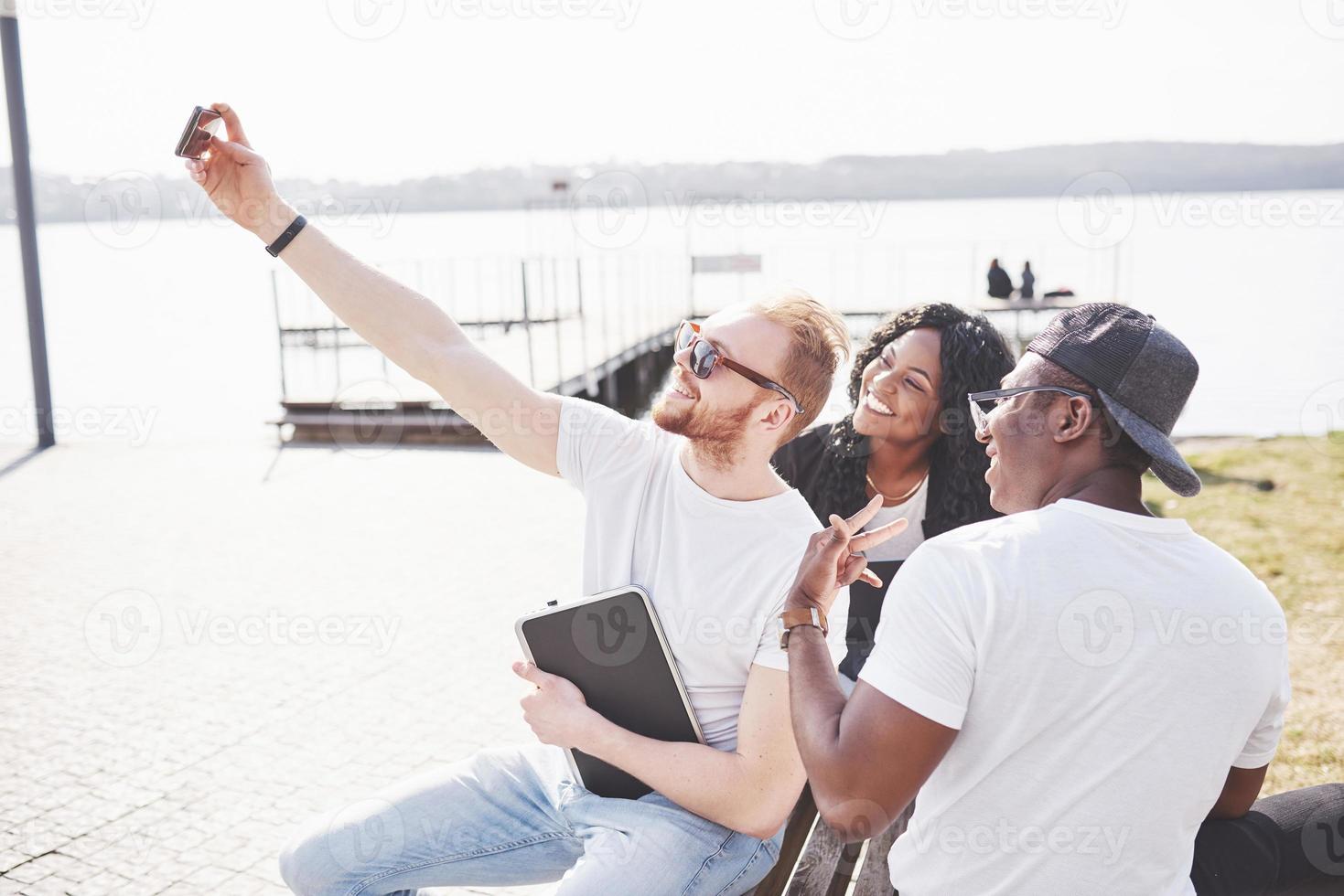 beaux amis multiethniques utilisant un ordinateur portable dans la rue et faire du selphie. concept de mode de vie des jeunes photo