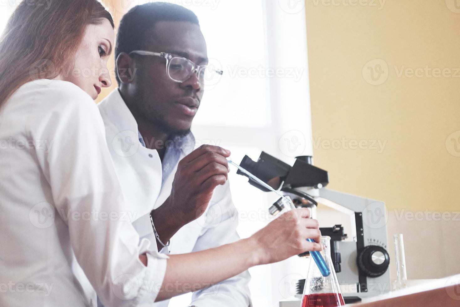 les scientifiques travaillent en étroite collaboration avec le microscope en laboratoire en menant des expériences et des analyses. photo