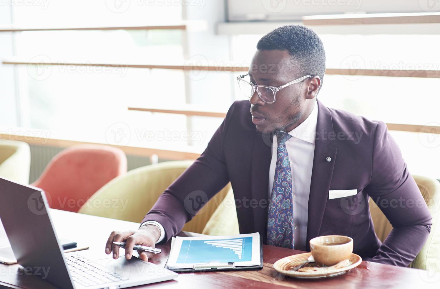 une belle femme d'affaires afro-américaine élégante portant un costume utilise son ordinateur portable tout en travaillant. photo