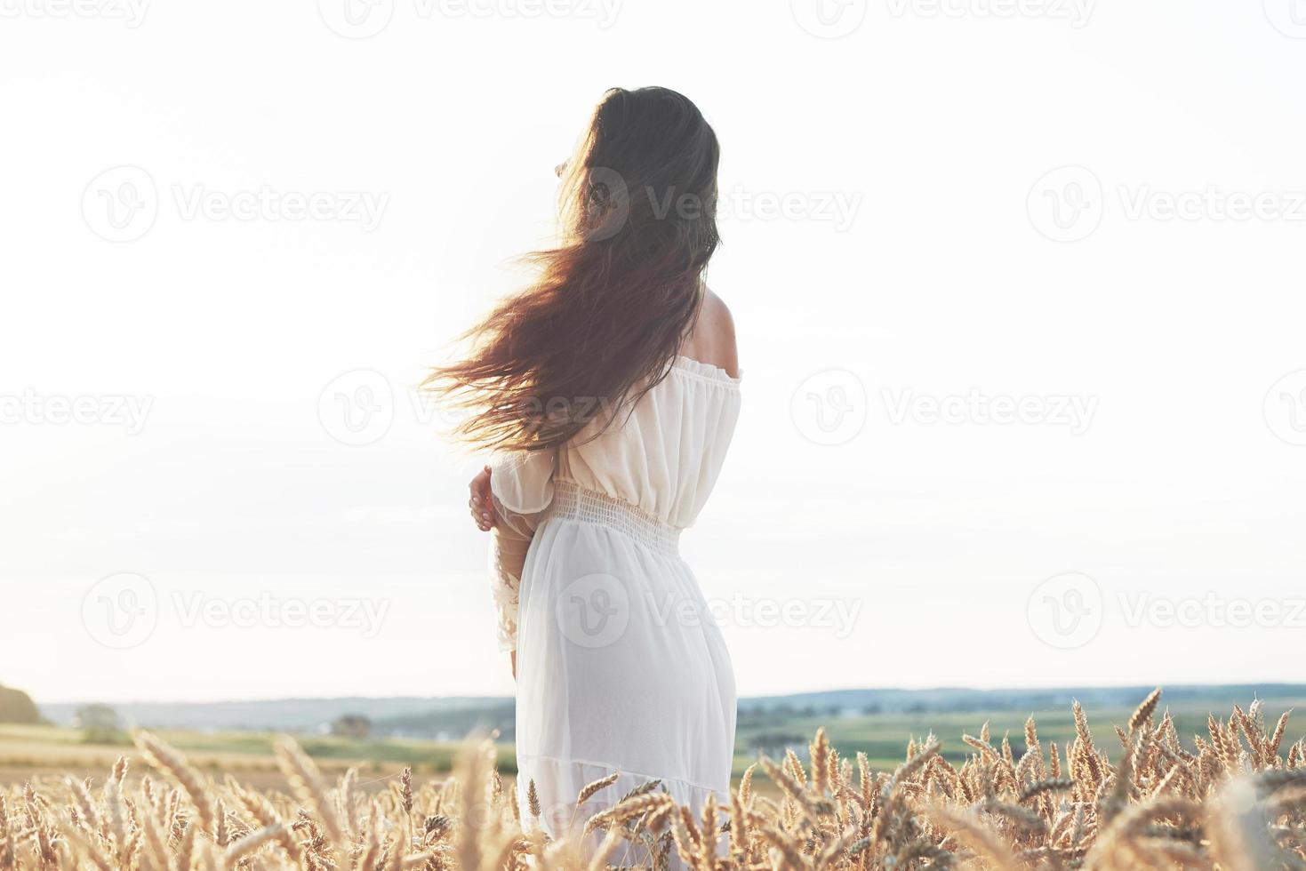 belle fille en robe blanche s'exécutant sur le champ de blé d'automne au coucher du soleil photo