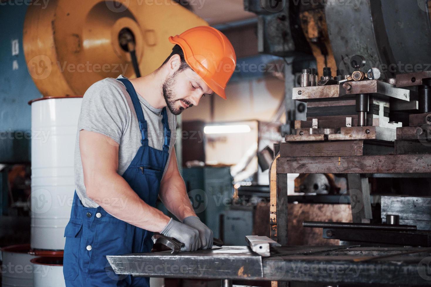 portrait d'un jeune travailleur portant un casque de sécurité dans une grande usine de recyclage des déchets. l'ingénieur surveille le travail des machines et autres équipements photo