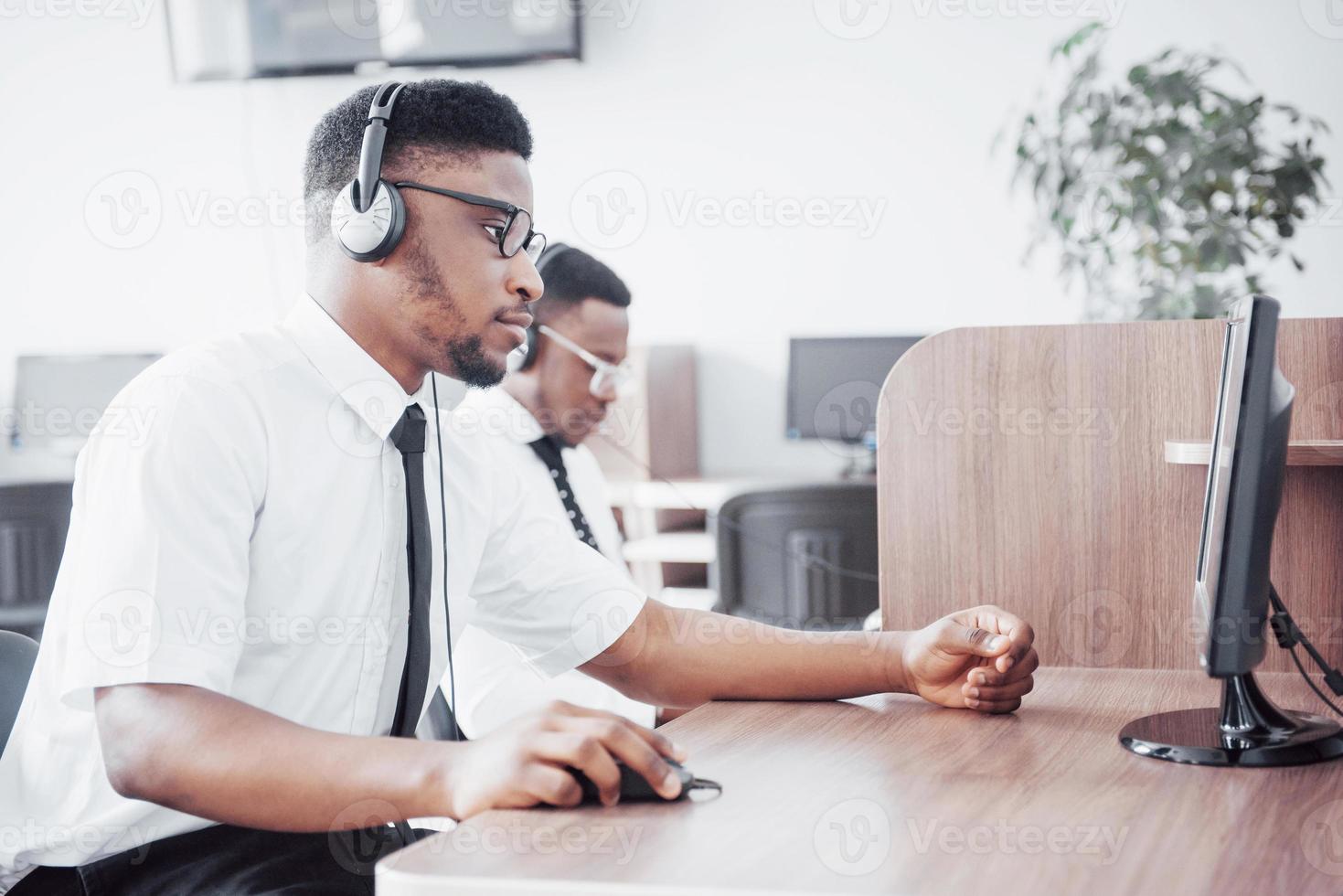 opérateur de support client afro-américain avec casque mains libres travaillant au bureau photo