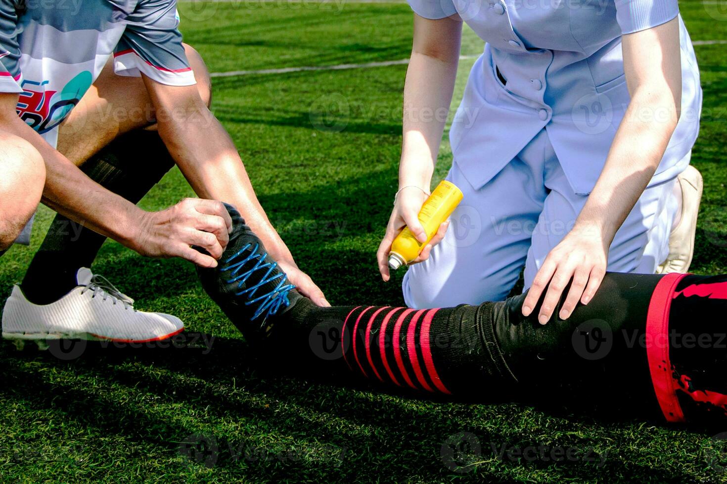 infirmière est portion une Football joueur qui blessé le sien jambe tandis que en jouant Football sur le herbe. photo