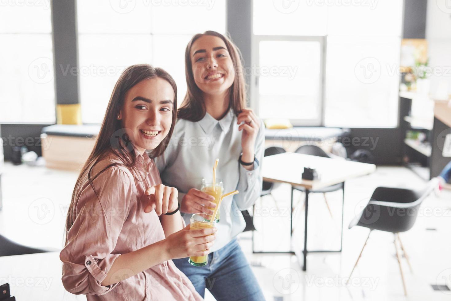 deux belles jumelles passent du temps à boire du jus. sœurs se détendre dans un café et s'amuser ensemble photo