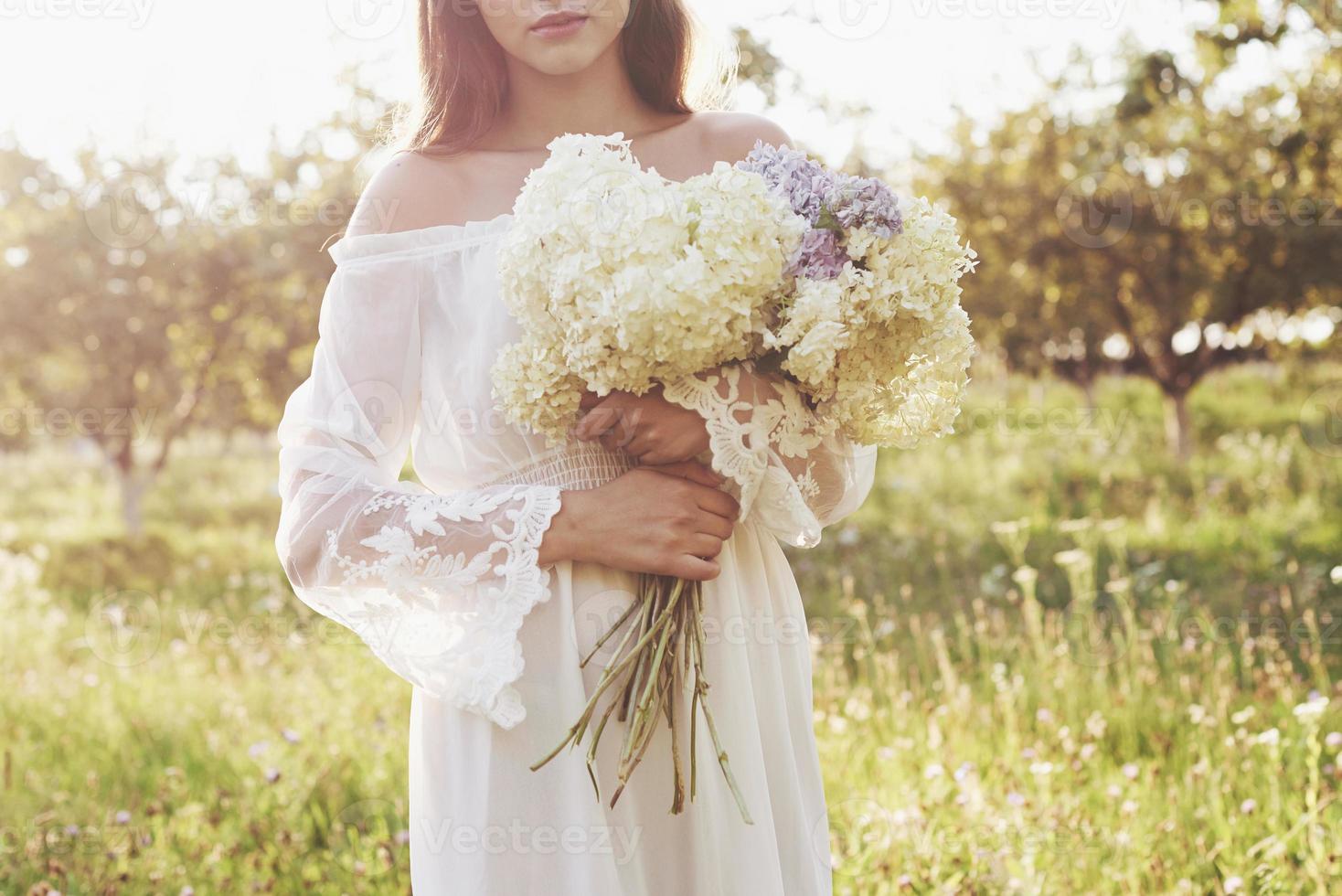 belle jeune femme vêtue d'une élégante robe blanche et profitant d'un bel après-midi ensoleillé dans un jardin d'été photo