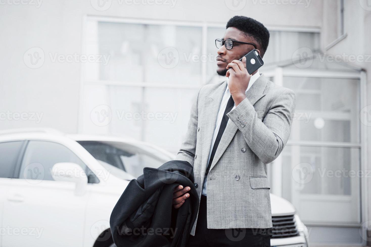 portrait d'un jeune homme d'affaires confiant marchant dans la ville parlant au téléphone portable photo