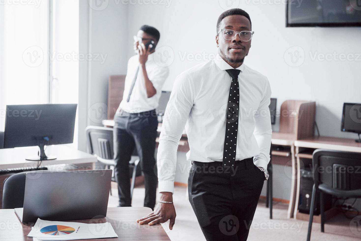 travailler avec le sourire. homme d'affaires africain heureux debout devant un collègue. photo