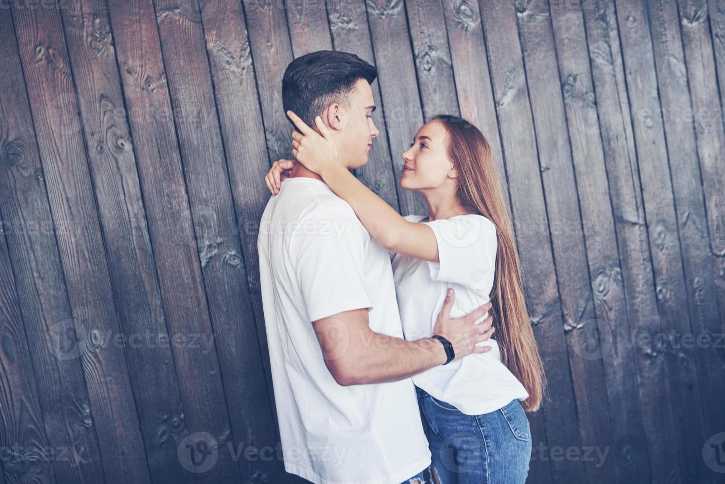 jeune couple, gars et fille ensemble sur un fond de mur en bois. ils sont heureux ensemble et habillés de la même manière. toujours dans la tendance photo