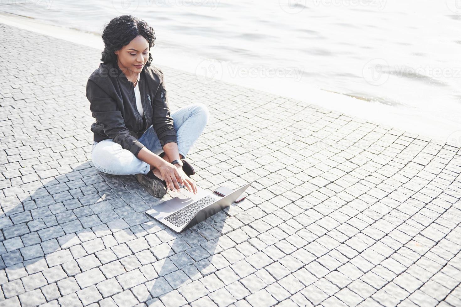 jeune femme dans la rue travaillant sur ordinateur portable photo