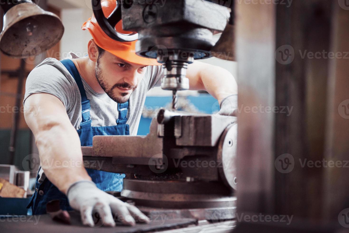 portrait d'un jeune travailleur portant un casque de sécurité dans une grande usine de recyclage des déchets. l'ingénieur surveille le travail des machines et autres équipements photo