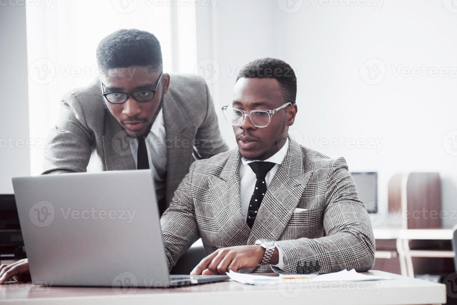 homme d'affaires moderne au travail. deux hommes d'affaires confiants en tenue de soirée discutent de quelque chose et regardent le moniteur d'ordinateur portable photo