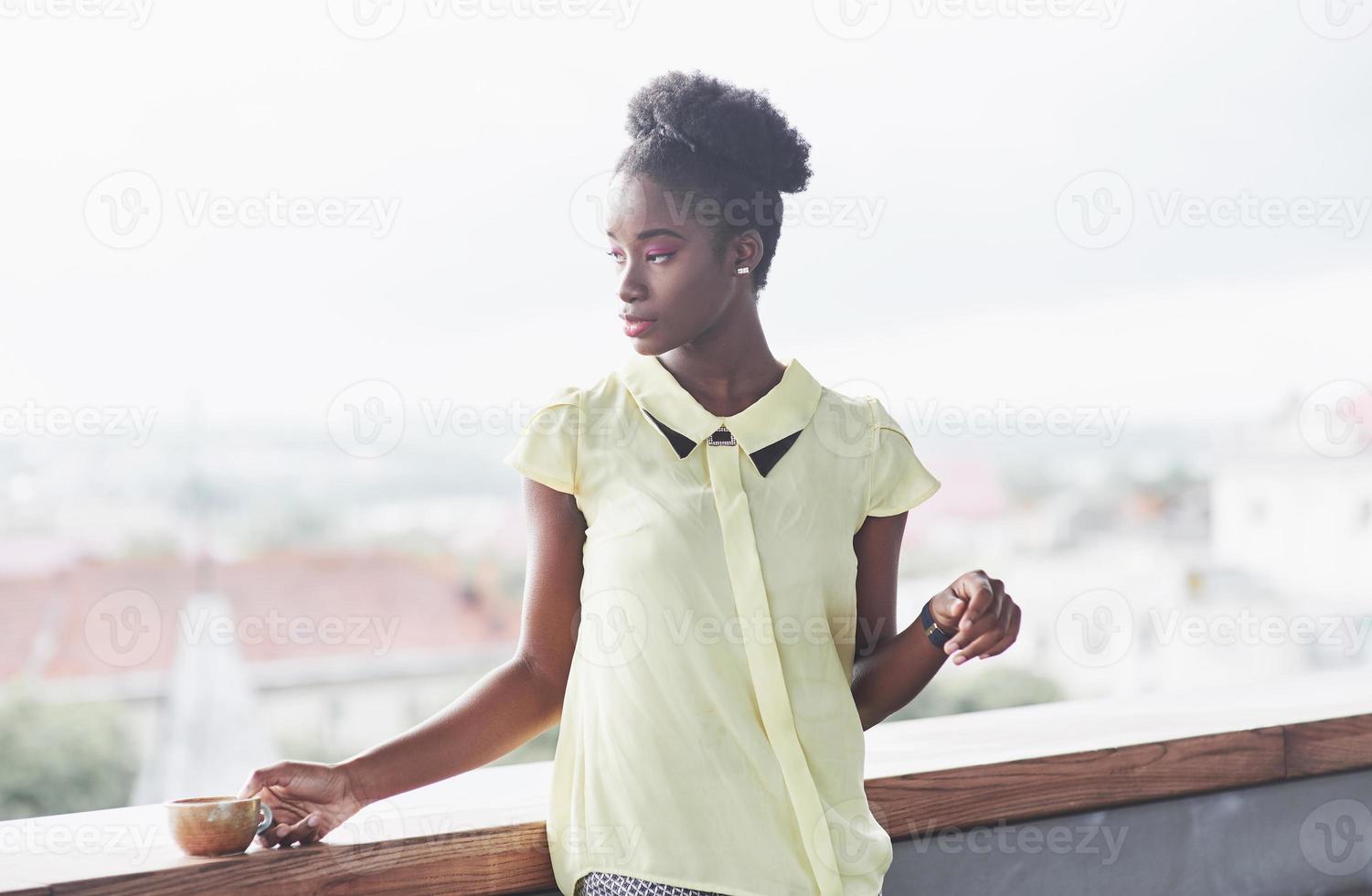 jeune fille afro-américaine aux cheveux noirs et bouclés pensif dans un café. bel endroit confortable. photo