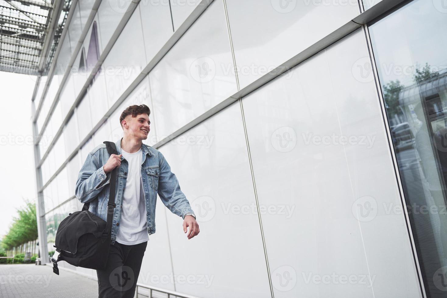 un beau jeune homme à l'aéroport attend le vol. photo