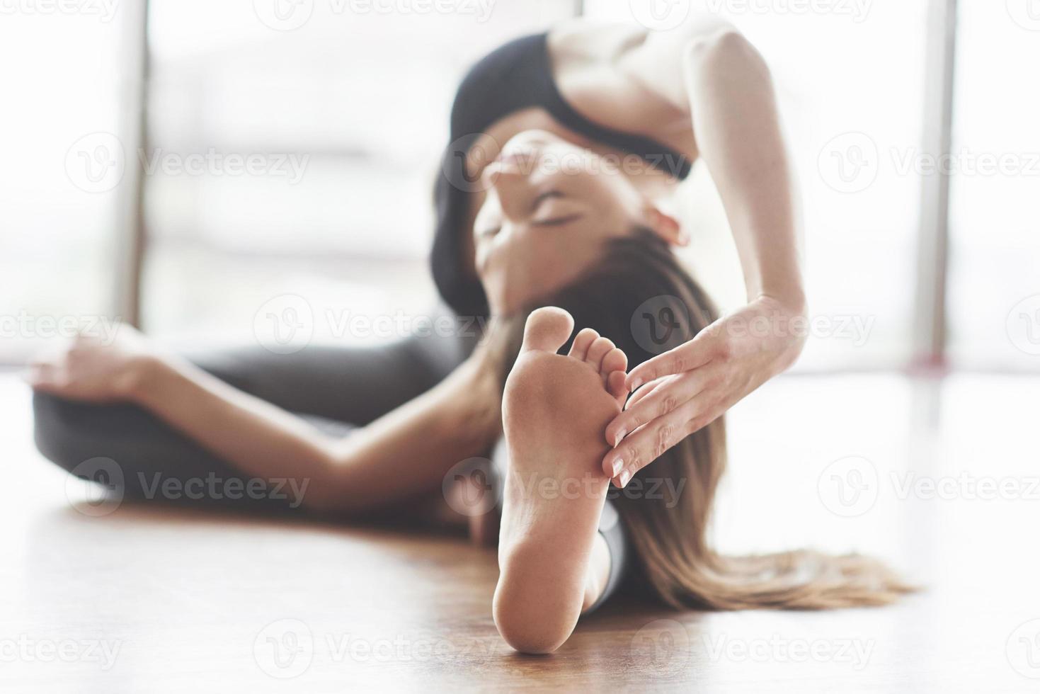 une belle femme de yoga pratique dans une salle de sport spacieuse et lumineuse avec de grandes fenêtres. photo