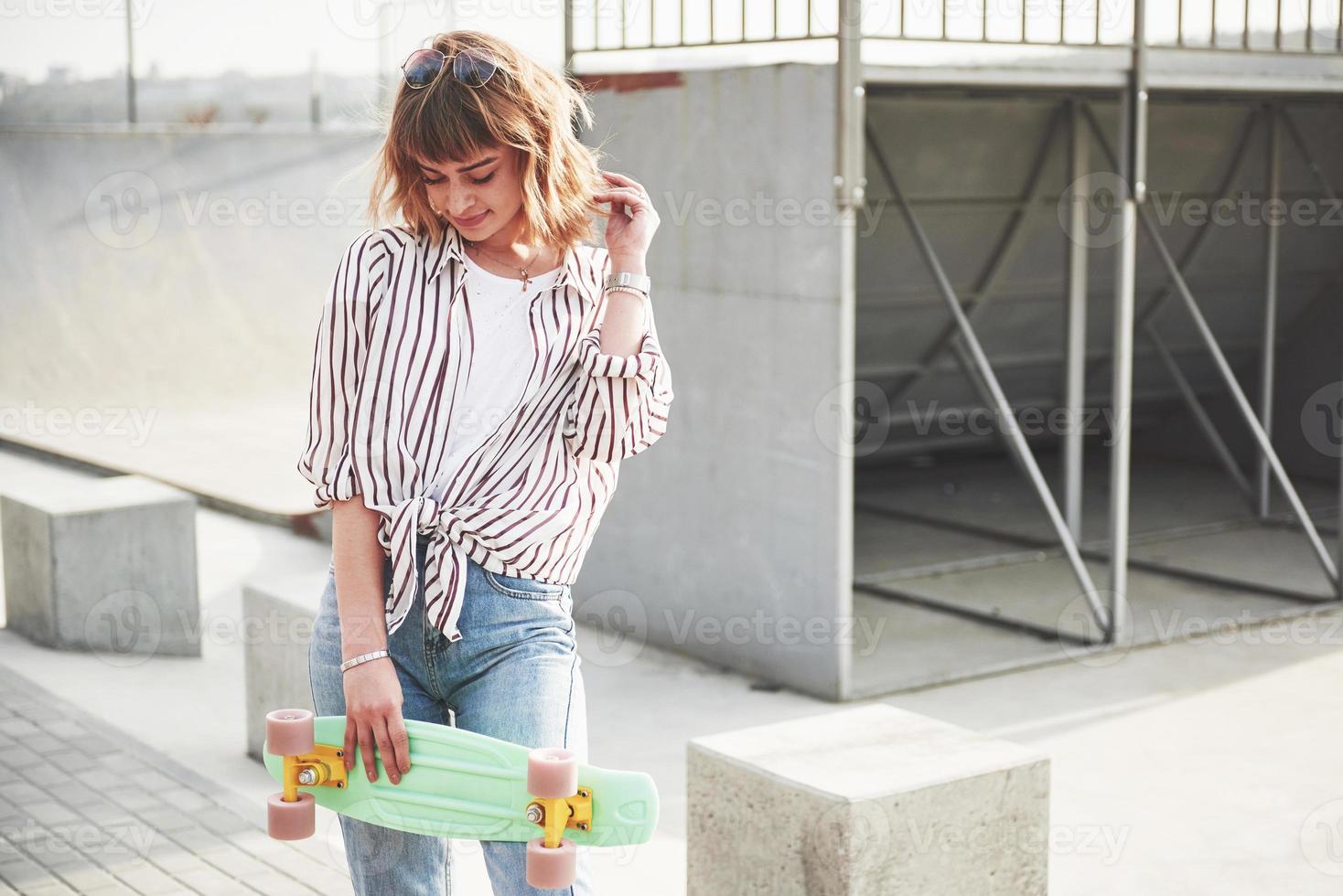 belle jeune femme élégante avec une planche à roulettes, par une belle journée ensoleillée d'été. photo