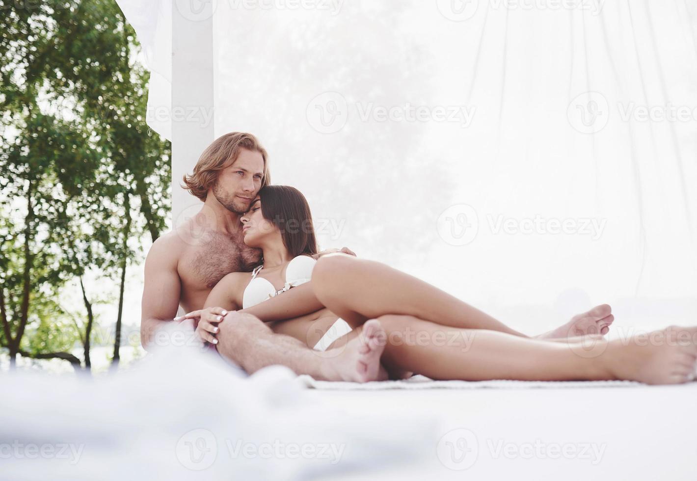 un beau couple se reposant sur la plage de sable, portant des vêtements de bain. atmosphère romantique photo