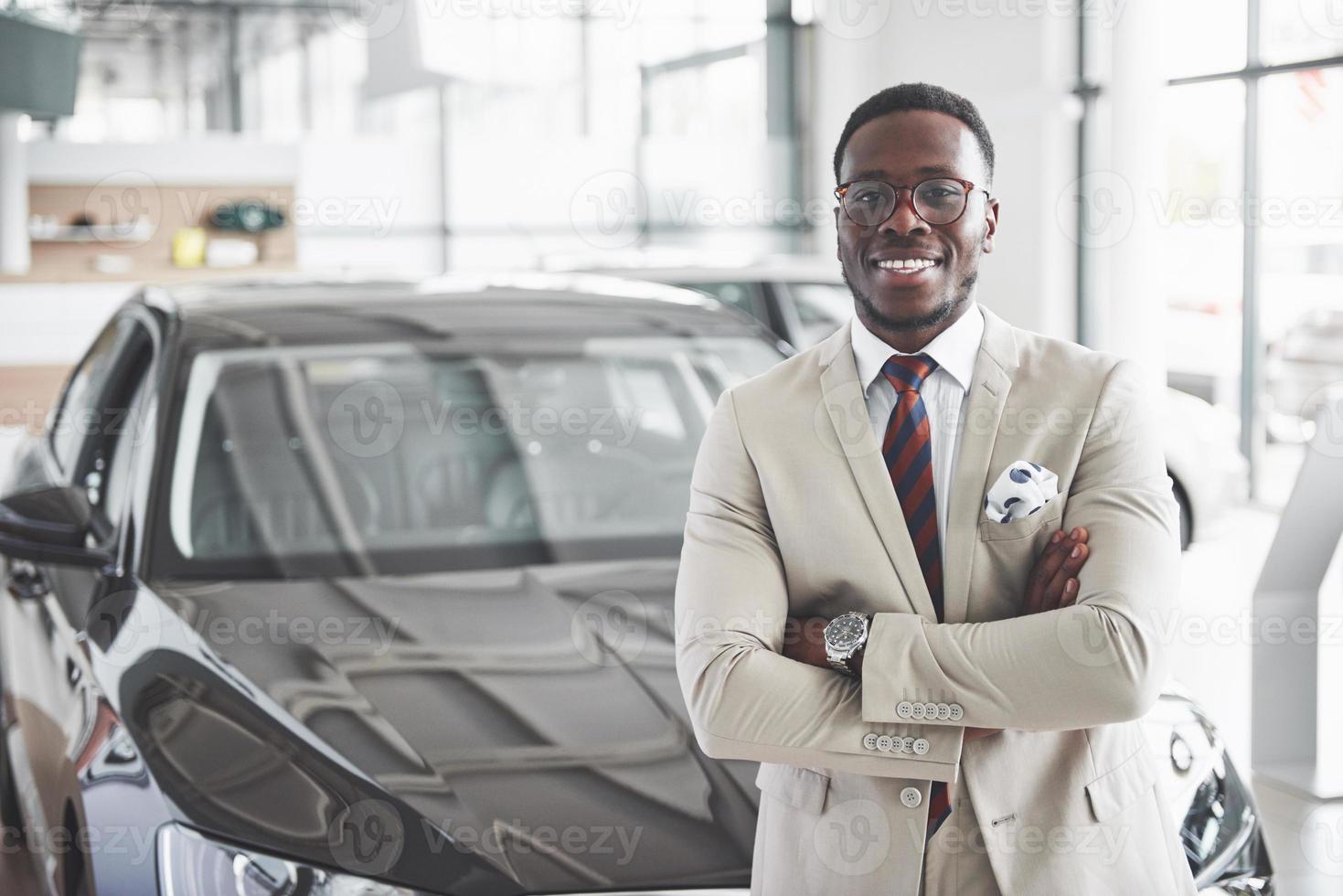 le jeune homme d'affaires noir séduisant achète une nouvelle voiture, les rêves deviennent réalité photo