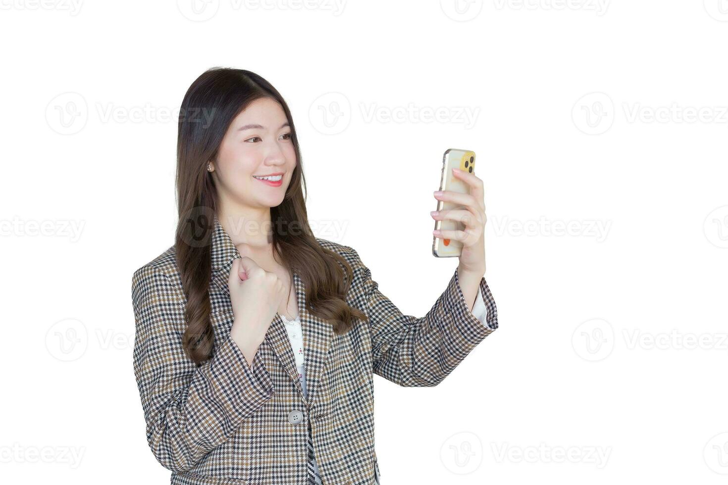 Jeune asiatique professionnel femme avec noir longue cheveux portant plaid costume tandis que elle actes prendre plaisir avec Succès de travail en utilisant téléphone intelligent tandis que isolé sur blanc Contexte. photo