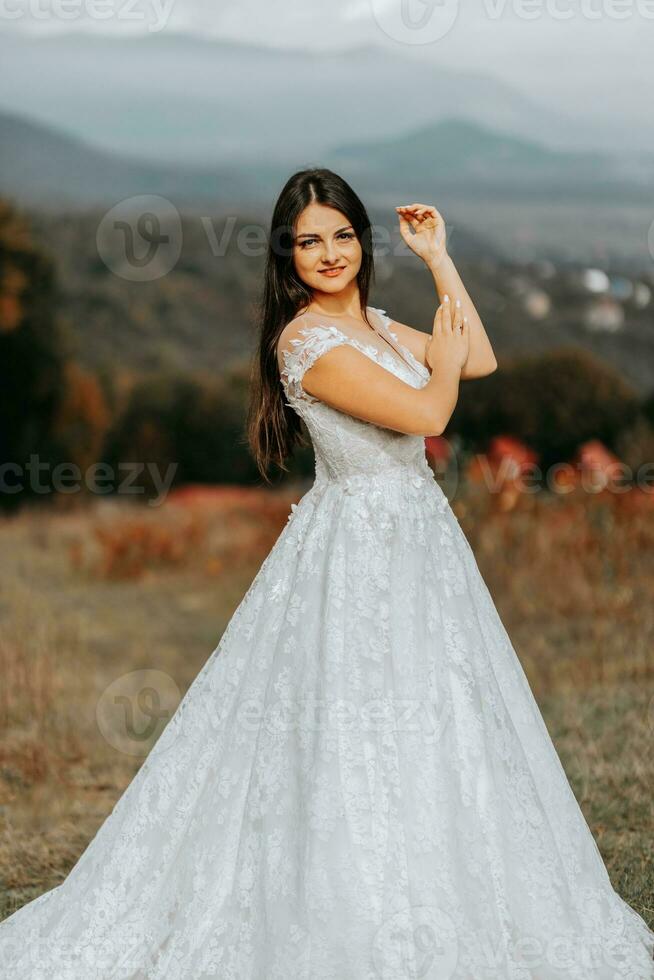 magnifique la mariée contre le Contexte de l'automne montagnes dans devant. une luxueux blanc robe. mariage la cérémonie sur Haut de le Montagne. gratuit espace. photo