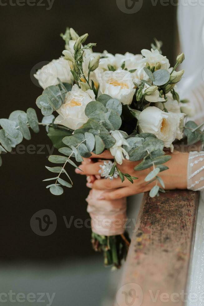 mariage portrait. une brunette la mariée dans une longue robe détient sa bouquet de des roses, pivoines et verdure. tondu photo. photo