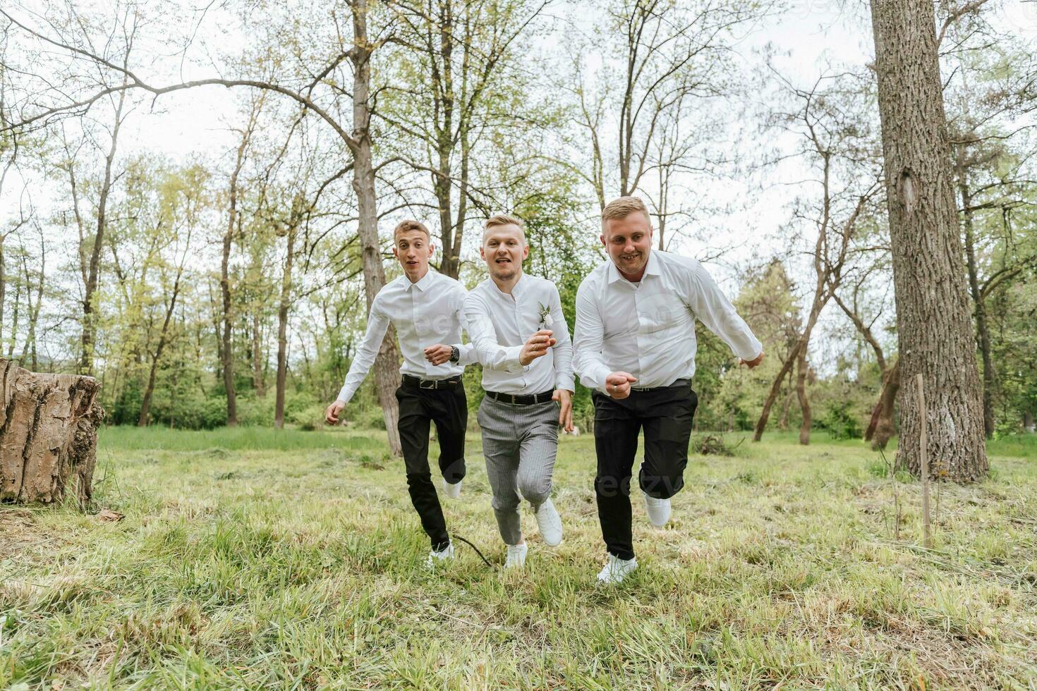 le jeune marié et le sien copains pose contre le Contexte de le forêt. ne pas une grand entreprise de gens ayant amusement. souriant garçons courir par le forêt et réjouir ensemble avec le jeune marié photo