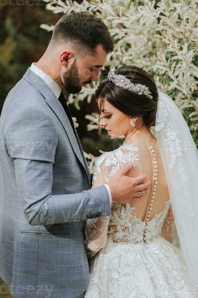 le la mariée dans une magnifique blanc robe avec manches et une couronne sur sa tête et une bouquet de hortensias dans sa mains photo