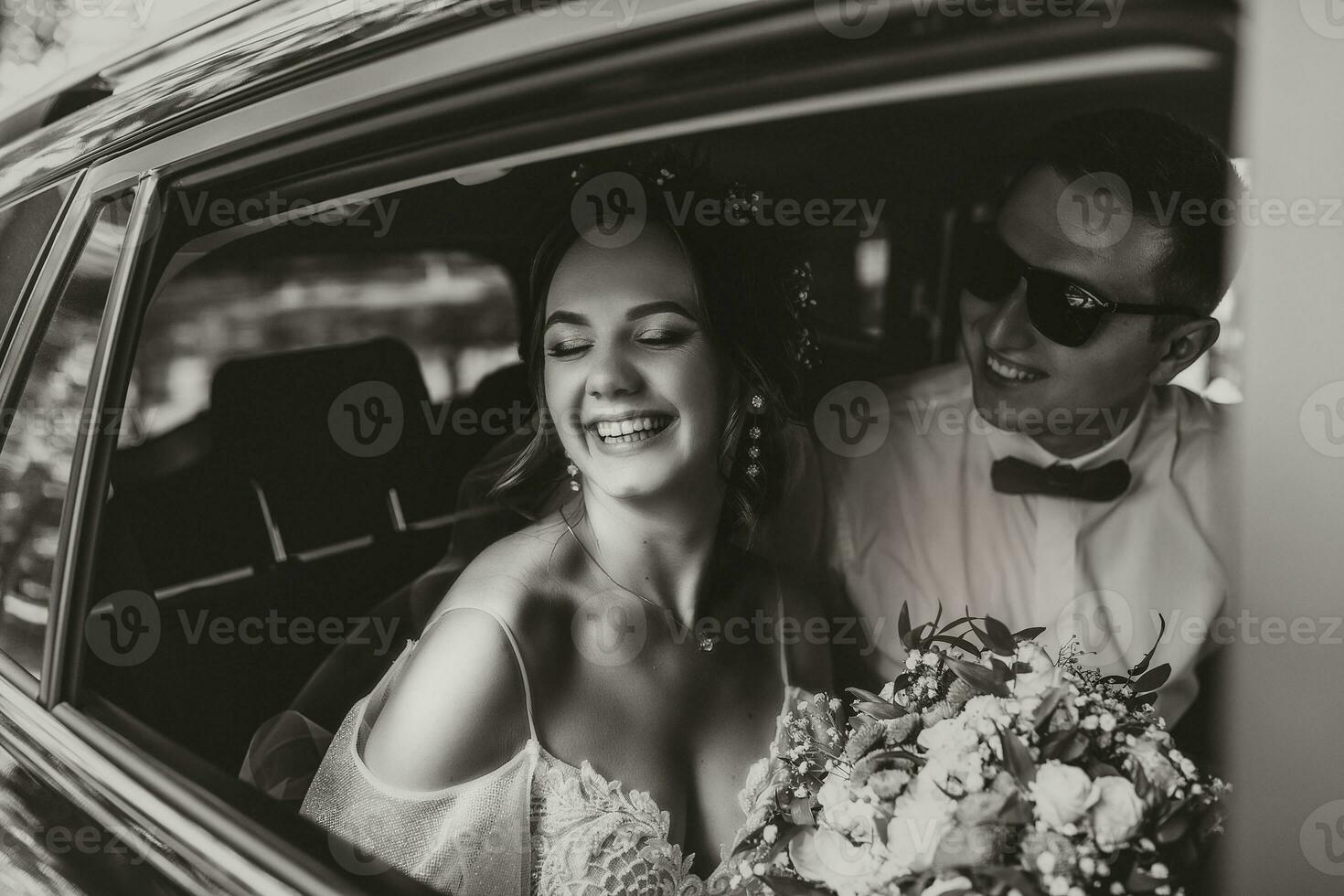 Jeune content la mariée et jeune marié sont réjouissance après le mariage la cérémonie dans leur voiture photo