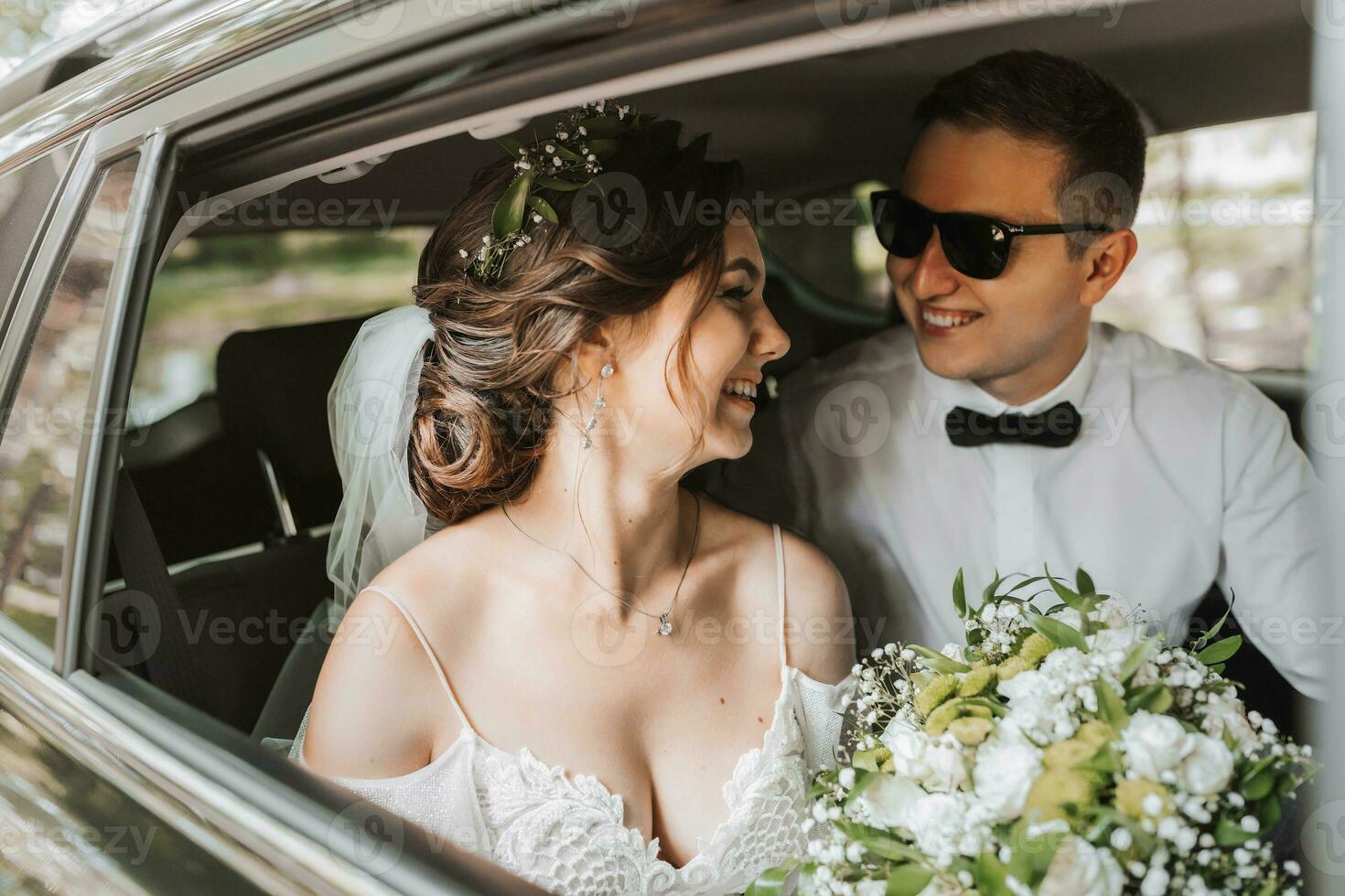 Jeune content la mariée et jeune marié sont réjouissance après le mariage la cérémonie dans leur voiture photo