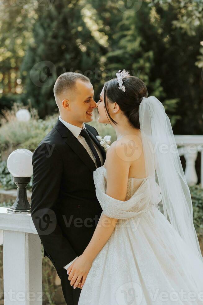 européen mariage couple dans le parc. le la mariée dans une magnifique robe avec une longue train et manches. jeune marié dans une classique costume photo