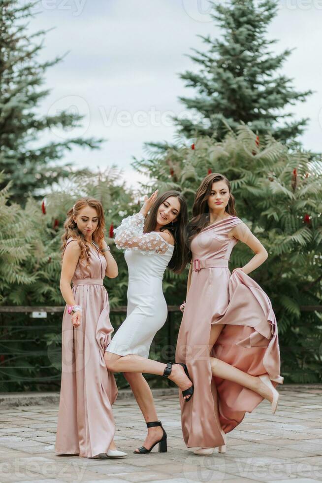 Trois Jeune magnifique souriant les filles dans à la mode vêtements. sexy insouciant femmes posant sur le rue. positif des modèles avoir amusement en plein air sur vert Contexte. de bonne humeur et content photo