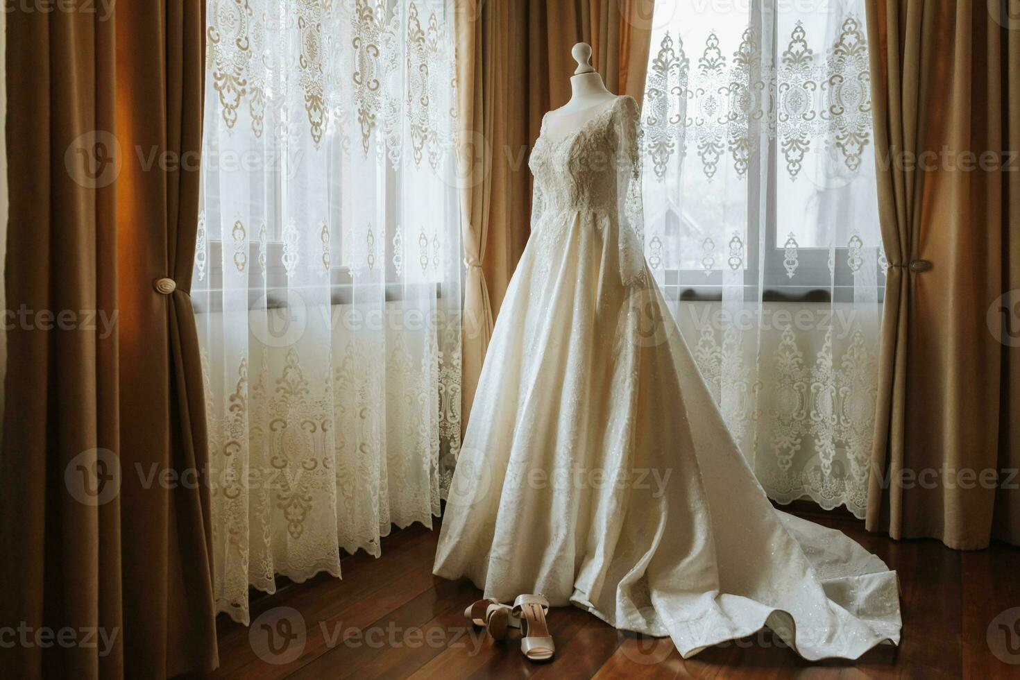 une luxueux dentelle mariage robe dans un coûteux intérieur de une Hôtel illuminé par Naturel lumière de une fenêtre sur deux côtés photo