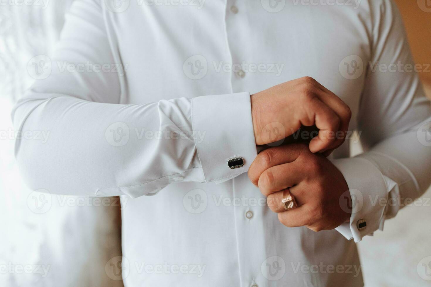 fermer de une homme et une boutonné chemise. Vêtements pour entretiens, travail et entreprise mode pour entreprise. le mains de une Masculin personne, le jeune marié est en train de préparer pour le mariage photo